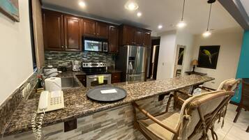 A modern kitchen with granite countertops, stainless steel appliances, and wooden cabinets.