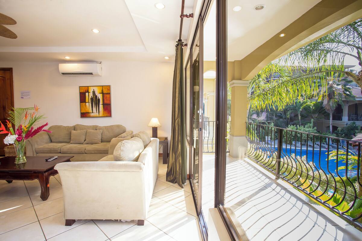A spacious living room with a sofa, a coffee table, and a painting on the wall.
