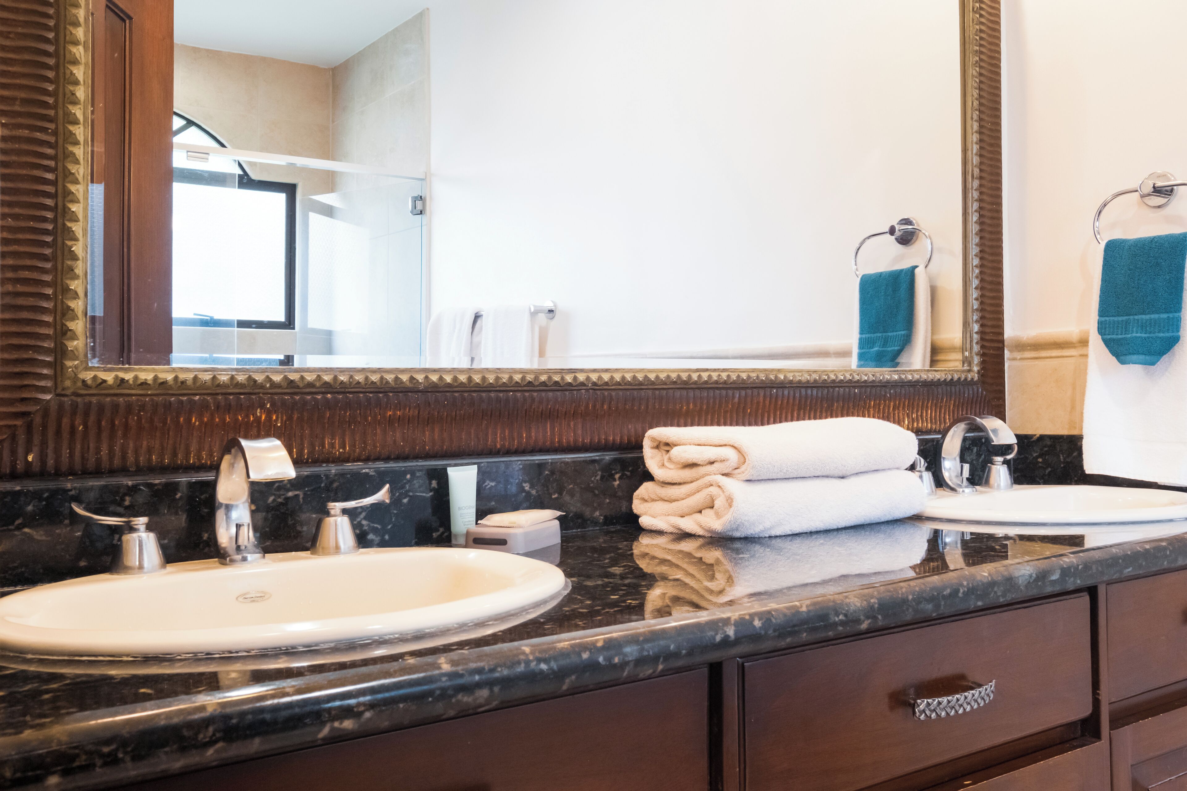 Une salle de bain avec un comptoir en marbre, un lavabo, un miroir et un porte-serviettes.