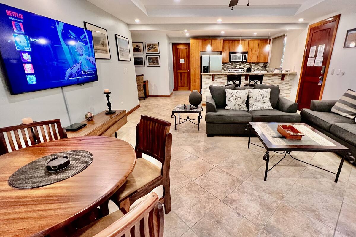 A modern living room with a TV, dining table, and sofas.