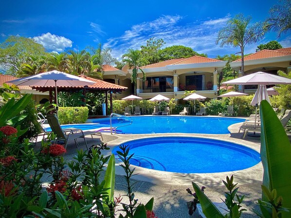 Un resort con una grande piscina, lettini e ombrelloni.