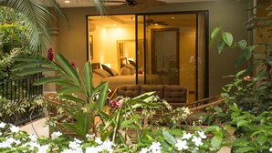 A room with a large sliding glass door leading to a balcony, a ceiling fan, and a bed with a headboard. - Monte Carlo Luxury Condominiums (Jacó)