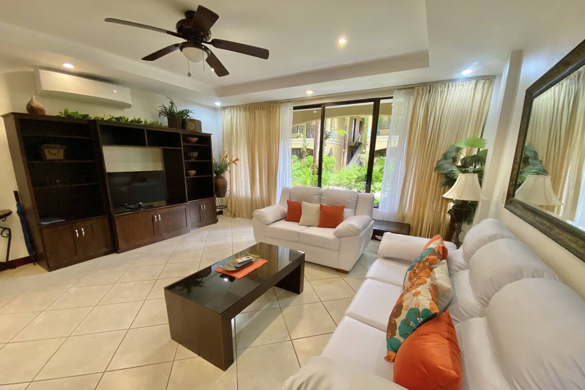 A living room with a sofa, a coffee table, a TV, and a ceiling fan.