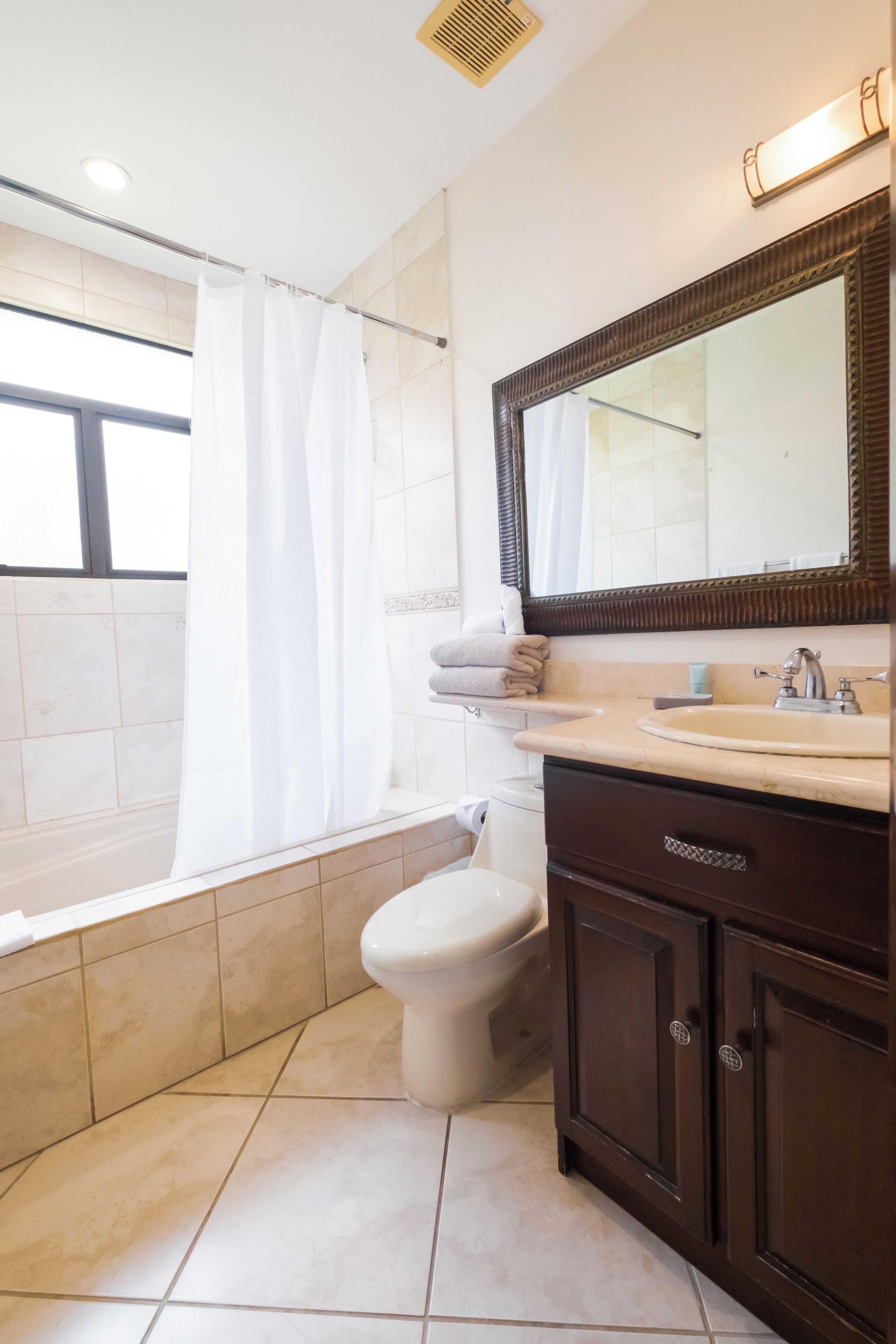 A bathroom with a toilet, sink, and mirror.