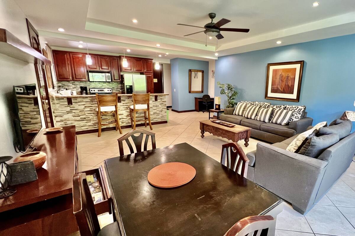 A modern living room with a sofa, coffee table, and dining area.