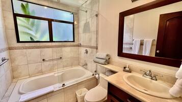 Un baño moderno con bañera, inodoro y dos lavabos.