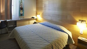 A hotel room with a large bed, a desk, and two bedside lamps.