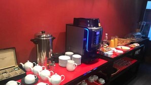 Un bufé de desayuno con máquinas de café, teteras, tazas y una variedad de alimentos.