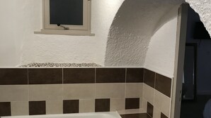 Un baño con bañera, ventana y pared de azulejos.