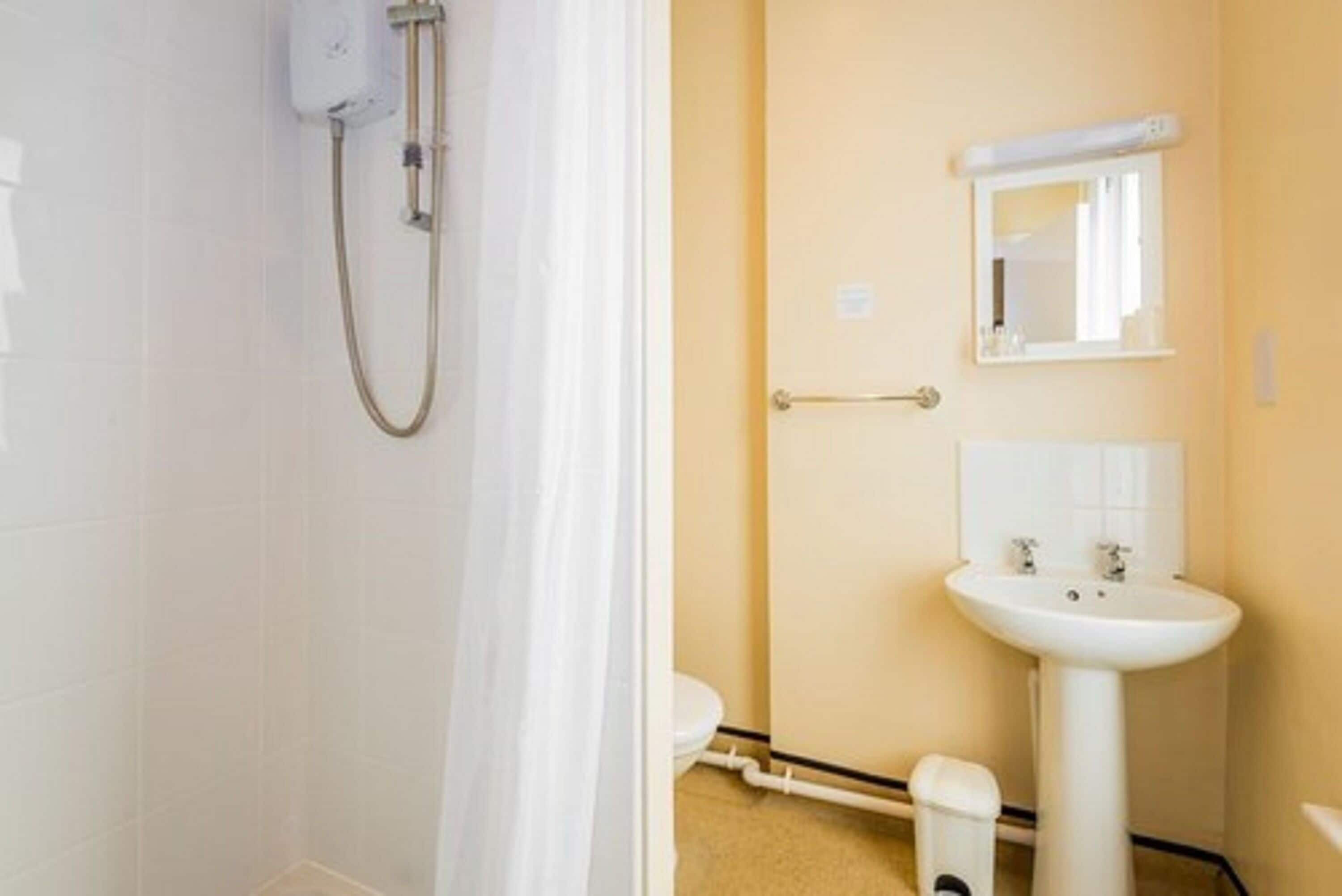 Un baño con ducha, inodoro, lavabo y espejo.