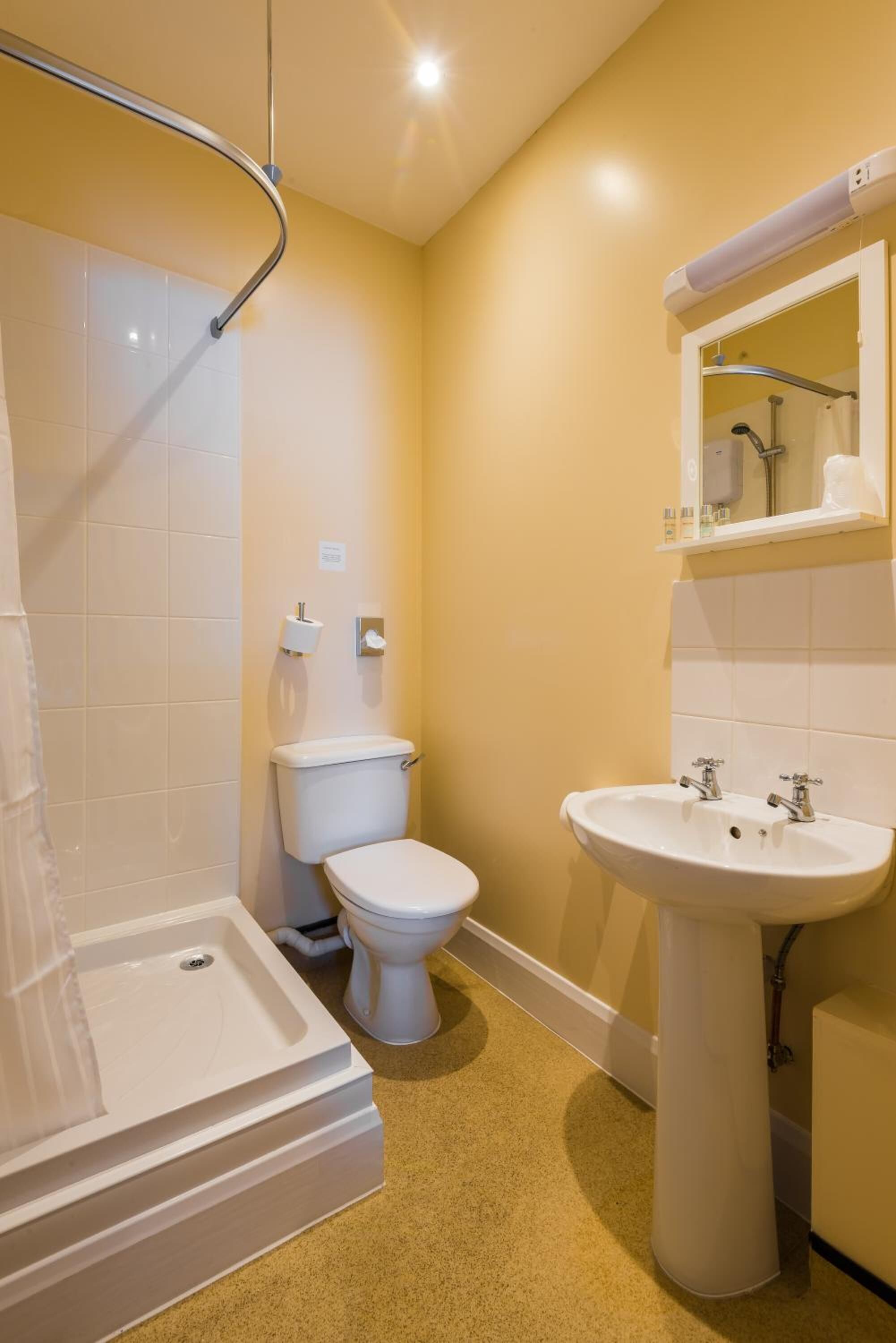 Une petite salle de bain comprenant une douche, des toilettes et un lavabo.