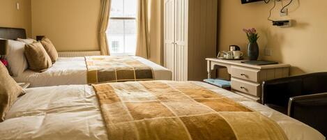 A hotel room with two beds, a desk, a chair, a TV, and a wardrobe.