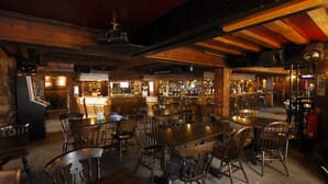A rustic bar area with wooden furniture, a bar counter, and a variety of bottles and glasses. - The Longboat Inn (Penzance)