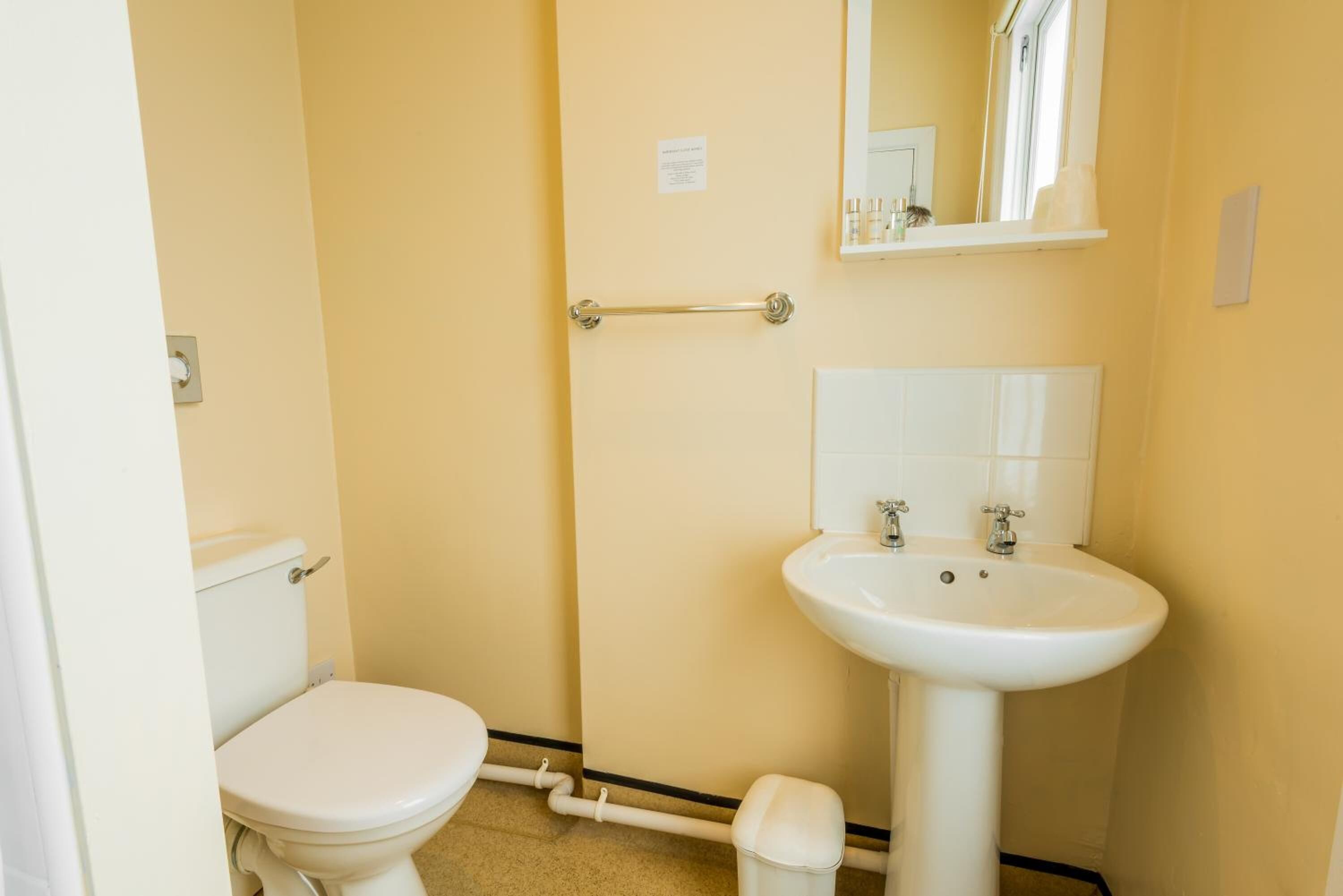 A small, compact bathroom with a toilet, sink, and mirror.
