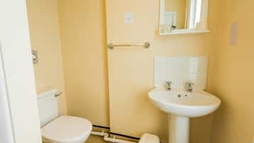 Un baño pequeño y funcional con inodoro, lavamanos y espejo.