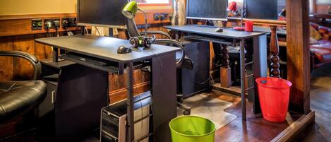 A workspace with desks, computers, and a green trash bin.