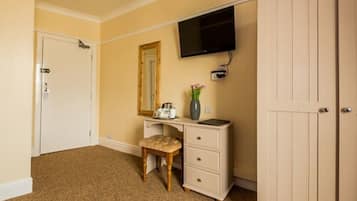 A bedroom with a bed, a dresser, a television, and a door.