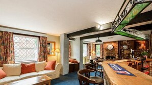 A bar area with a wooden counter, bar stools, and a clock on the wall. - The Well guesthouse (Marlborough)
