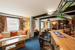 Eine Bar mit einer Holztheke, Barhocker und einer Uhr an der Wand.