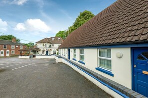 A row of buildings with a blue door, a parking lot, and a clear sky. - The Well guesthouse (Marlborough)