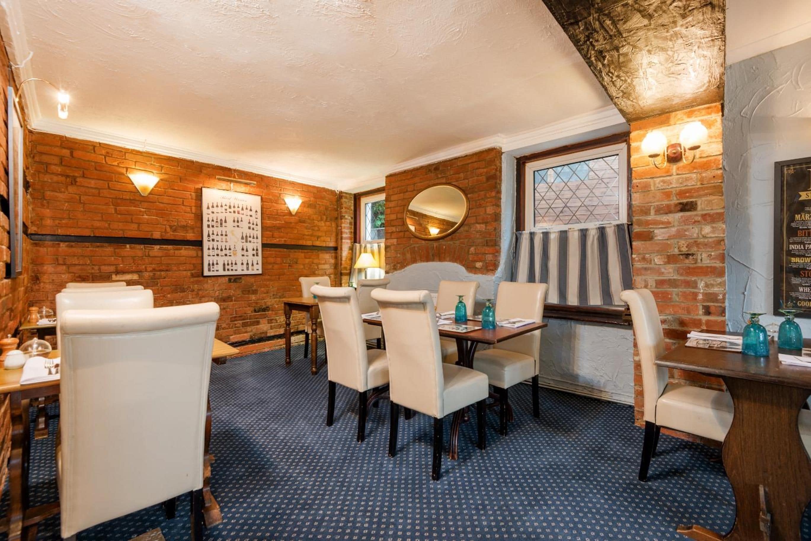 A restaurant with brick walls, a menu board, and a dining area with tables and chairs.