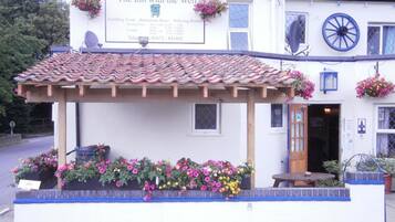 Un edificio blanco con un cartel anunciando The Inn with the Well, que muestra los horarios de apertura y un número de teléfono.