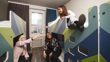 Ein Schlafsaalzimmer mit Etagenbetten, einem Fenster mit Vorhängen und einer Heizung.