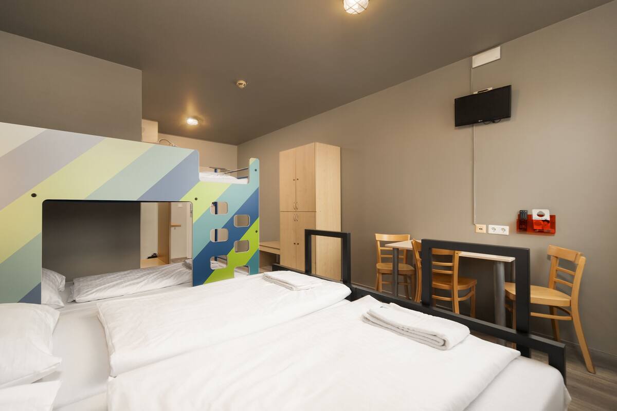 Ein Hotelzimmer mit einem Etagenbett, einem Schreibtisch und einem Fernseher.