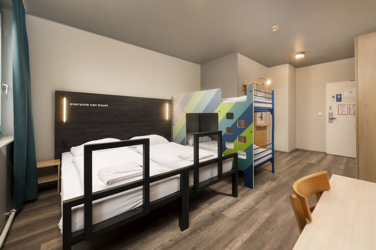 Ein modernes Hotelzimmer mit Stockbett, einem kleinen Tisch und einem Schreibtisch.