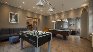 A modern indoor recreational area with a foosball table, pool table, and seating area. - a&o Wien Stadthalle (Vienna)