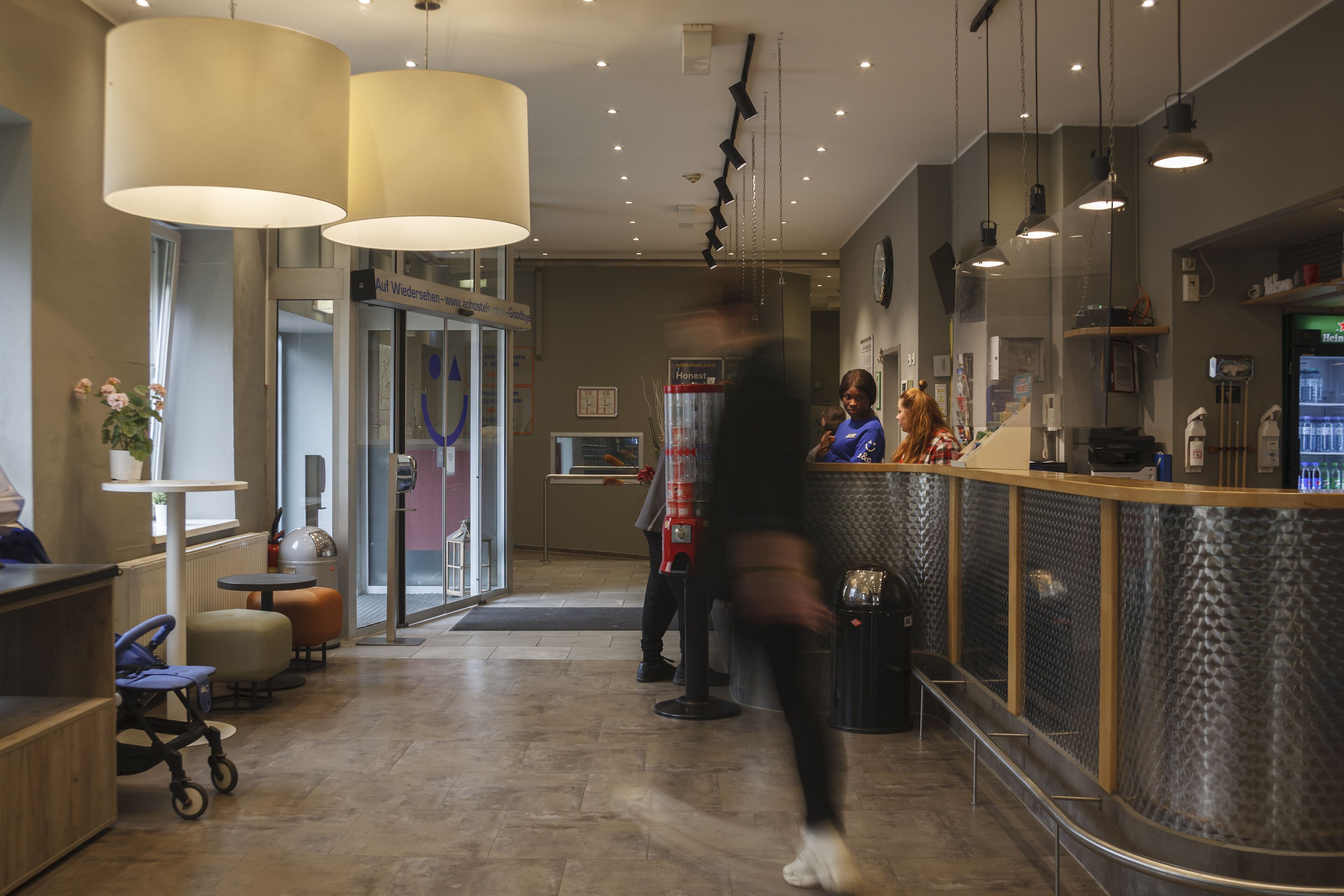 A hotel lobby with a reception desk, seating area, and a glass door entrance.