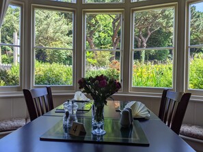 A dining table with a number 4 placemat, a vase with flowers, salt and pepper shakers, and a folded napkin. - The Denes Guest House (Lynton)