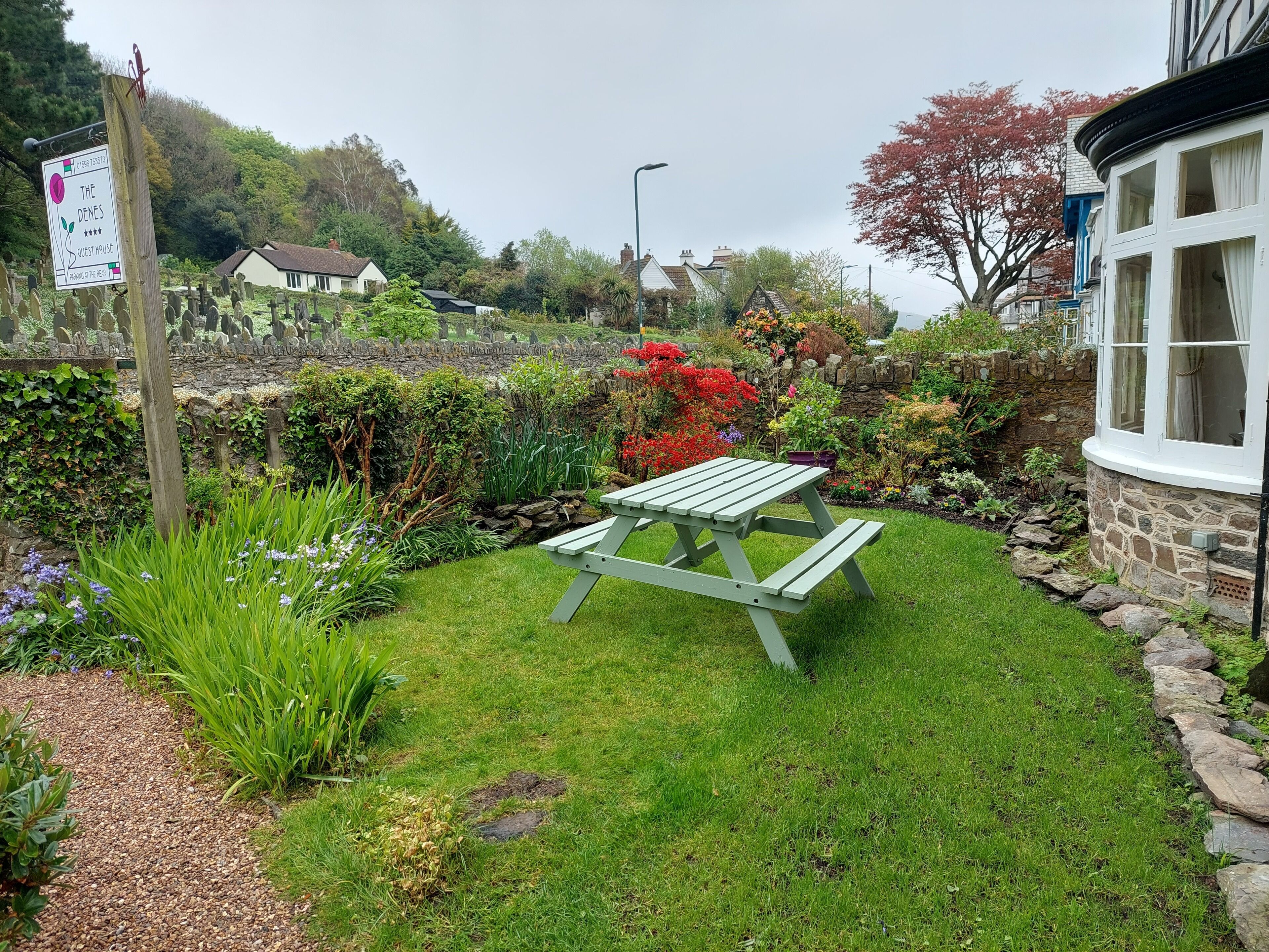 A garden with a picnic table, a stone wall, and a sign indicating a guest use area.