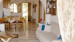 Un grand espace de vie comprenant un canapé, une table à manger et des chaises. On y trouve également une bibliothèque et une fenêtre avec des rideaux.