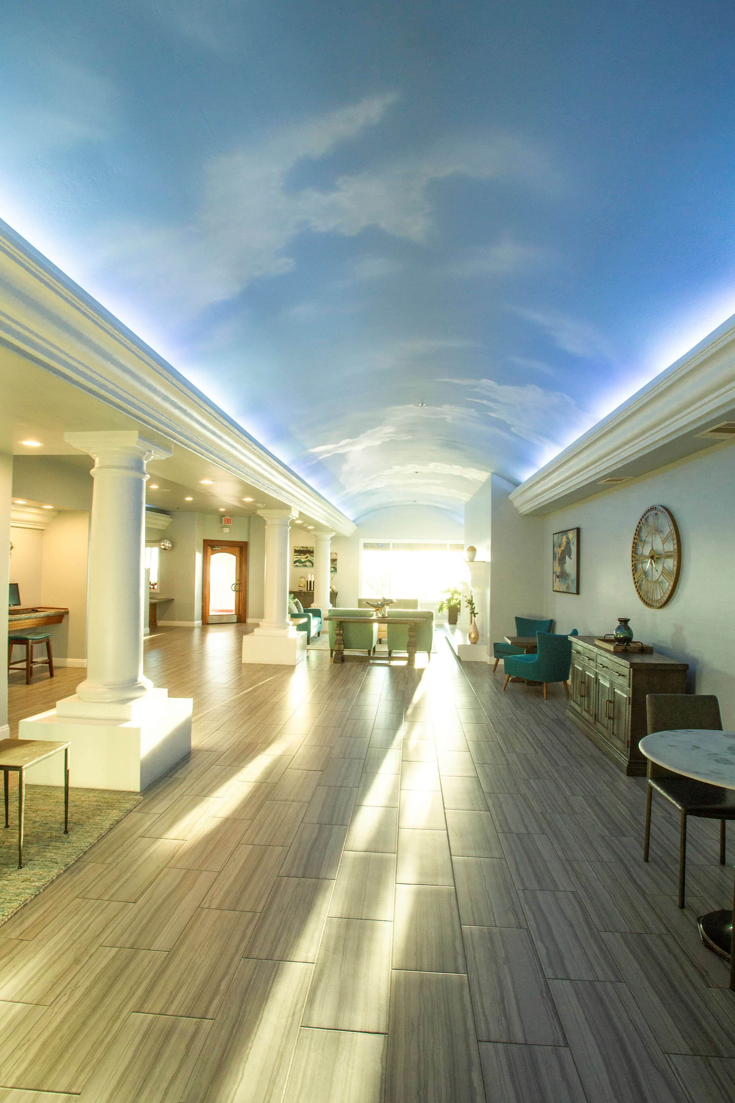 A spacious lobby with a high ceiling, columns, and a seating area with chairs and a sofa.