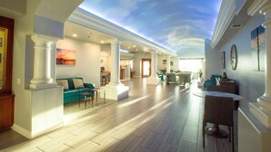 A spacious interior with a high ceiling, a skylight, and a modern open-plan layout with seating areas and a dining space. - Tamarack Beach Resort Hotel (Carlsbad)