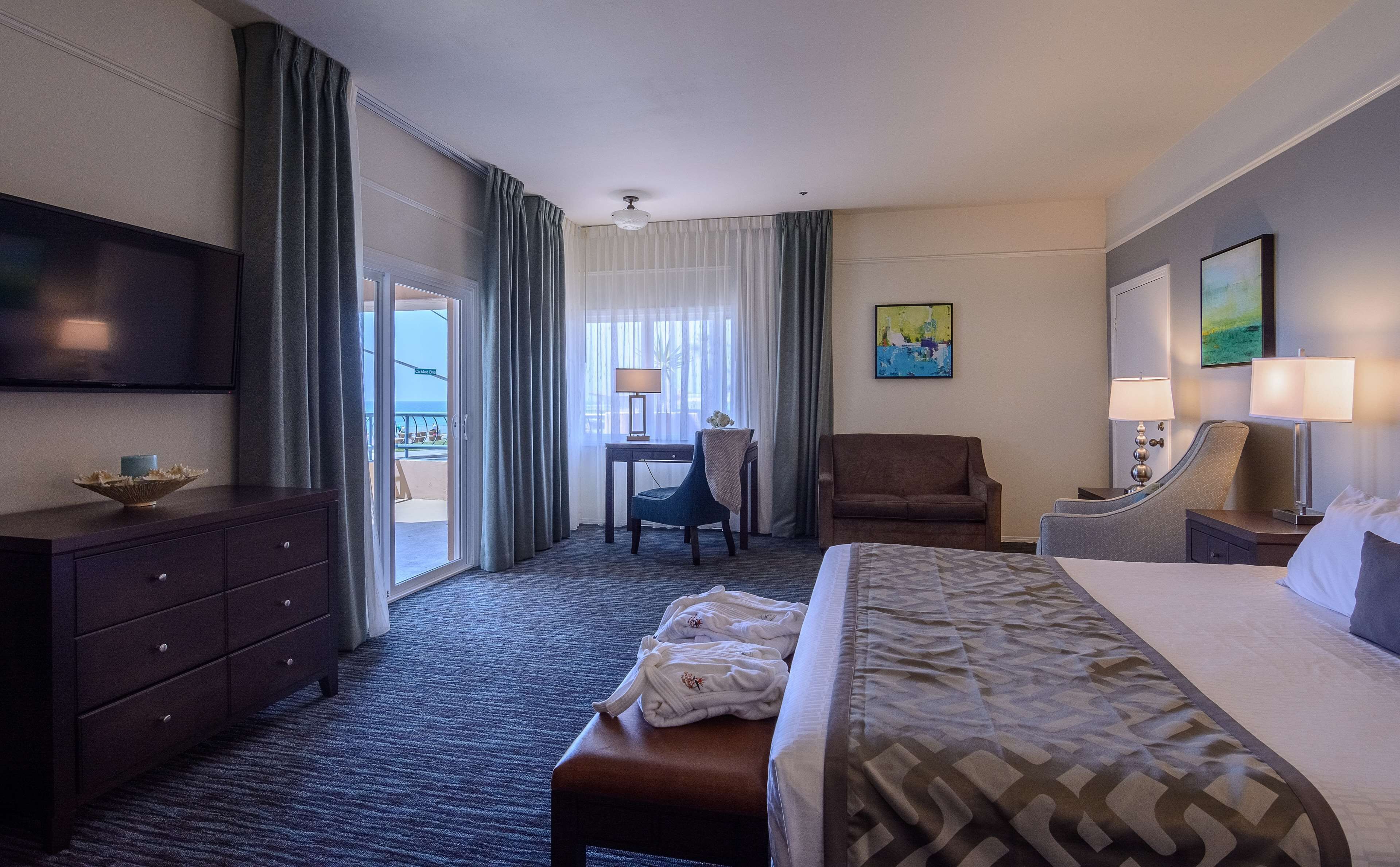 Habitación de hotel con una cama, un escritorio, una silla, un televisor y vistas al exterior.
