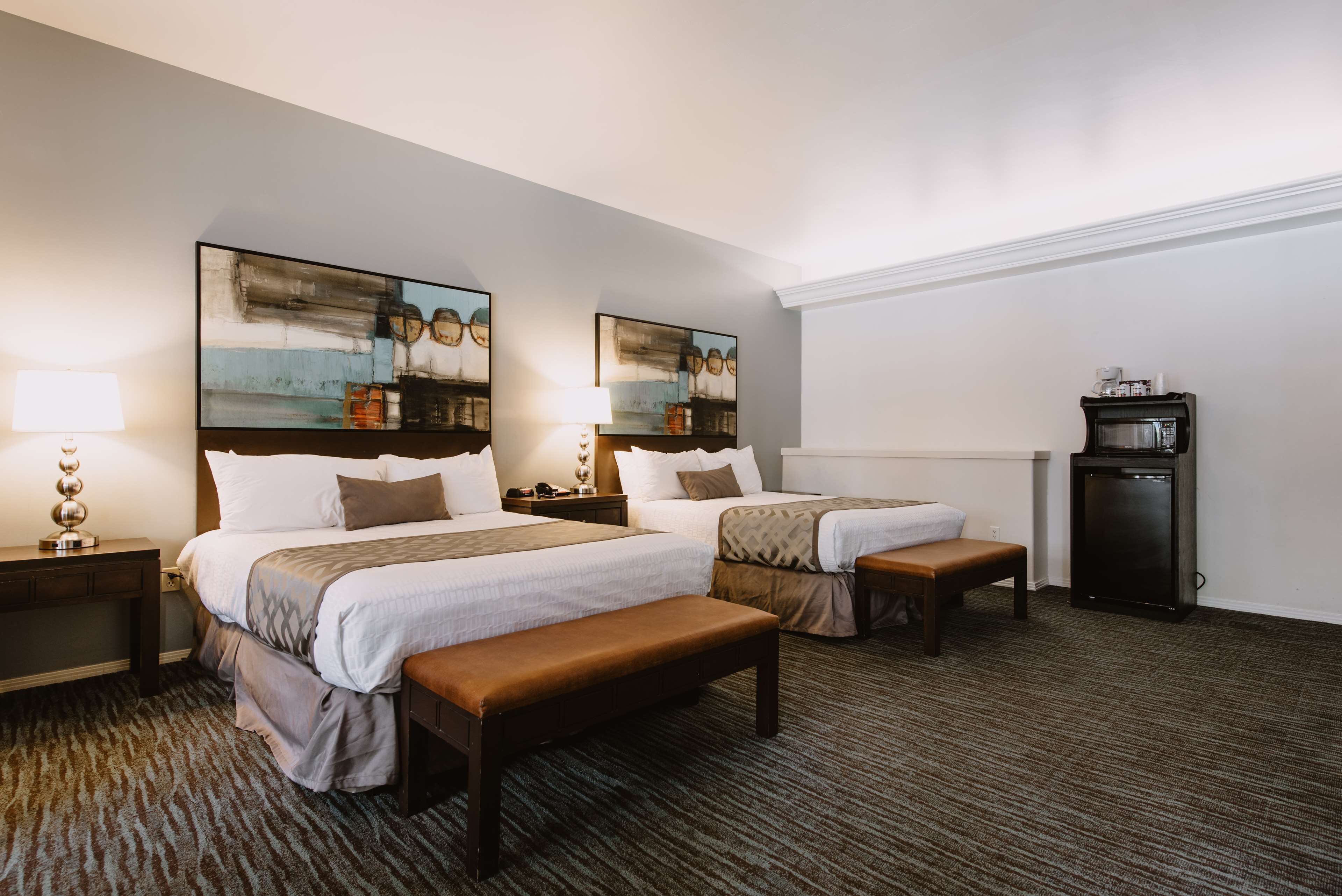 A hotel room with two beds, a bench, a small table, and a TV.