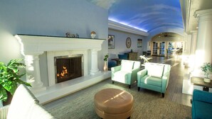 A living room with a fireplace, seating area, and a view of the kitchen. - Tamarack Beach Resort Hotel (Carlsbad)