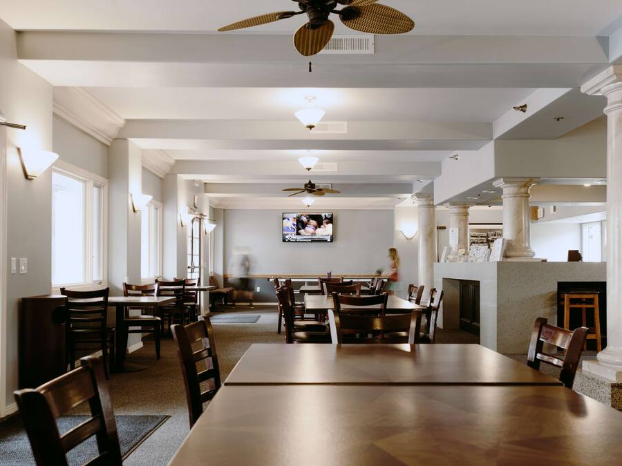Un comedor espacioso con techos altos, candelabros y un televisor montado en la pared.