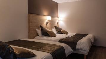 A hotel room with two beds, wooden headboard, and wall-mounted lamps.