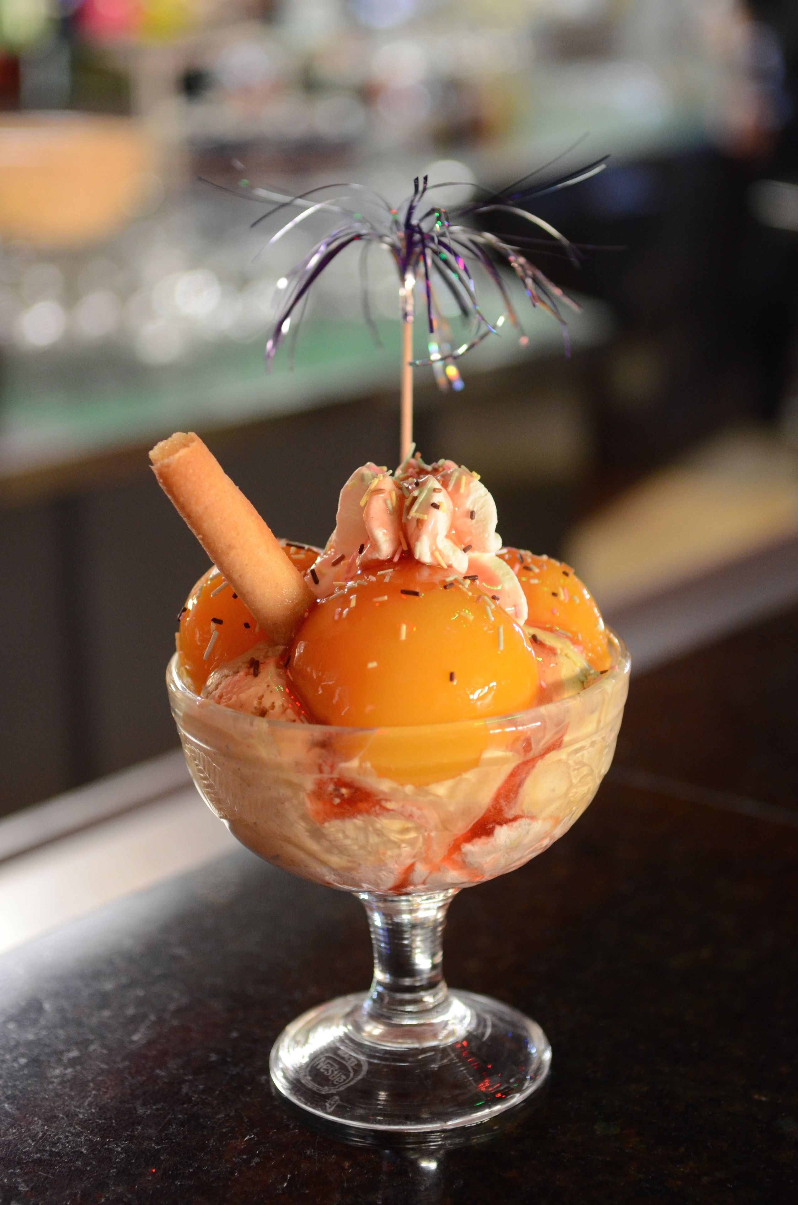 A dessert in a glass bowl with a stick on top.