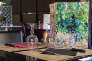 Una mesa dispuesta con un menú, copas de vino y una botella.