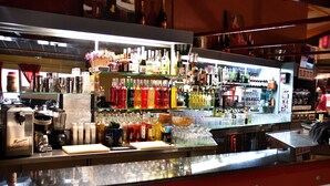 Un espace bar avec des étagères remplies de différentes bouteilles et de verres.
