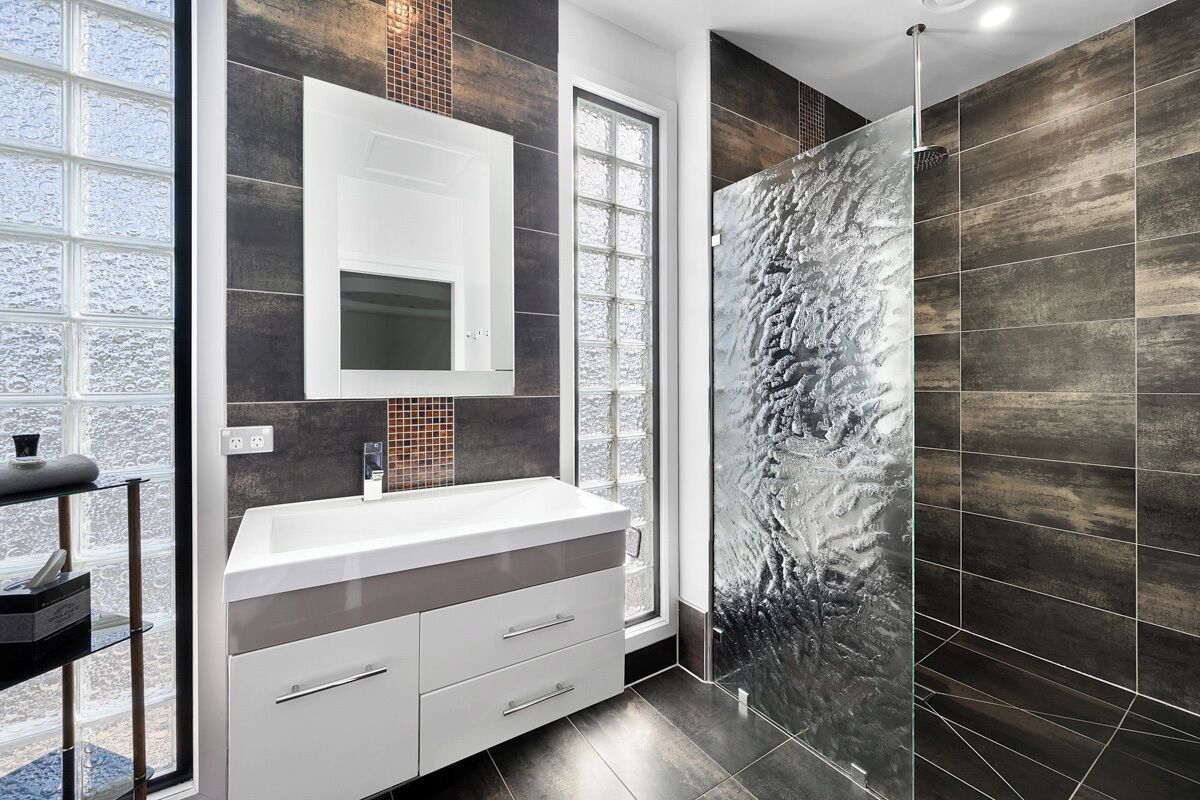 Un bagno moderno con uno specchio grande, un mobile lavabo bianco e un box doccia in vetro.