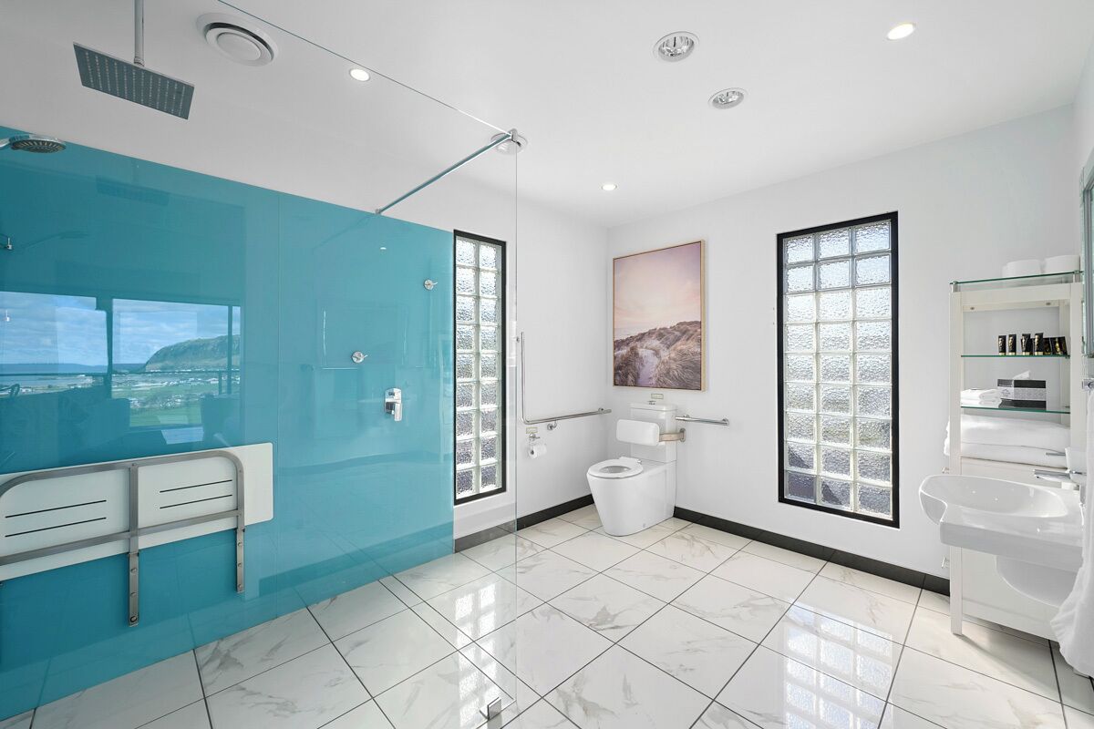 A modern bathroom with a blue shower enclosure, a toilet, and a sink.