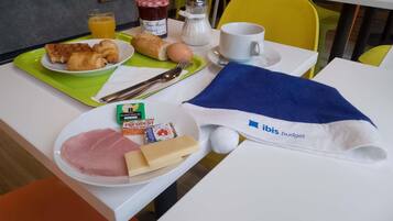 A breakfast setup with croissants, ham, cheese, and a drink on a table with a napkin and utensils.