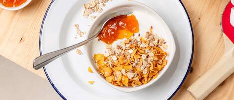 Un tazón de cereal con leche y trozos de fruta en un plato.