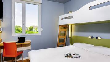 Una cama litera con escalera, un escritorio con una computadora portátil y una ventana con vista a follaje.