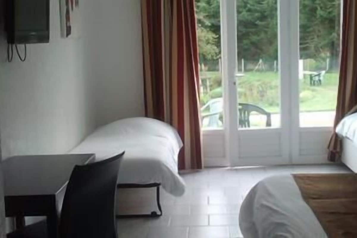 Ein Hotelzimmer mit zwei Einzelbetten, einem Schreibtisch und einem Stuhl.